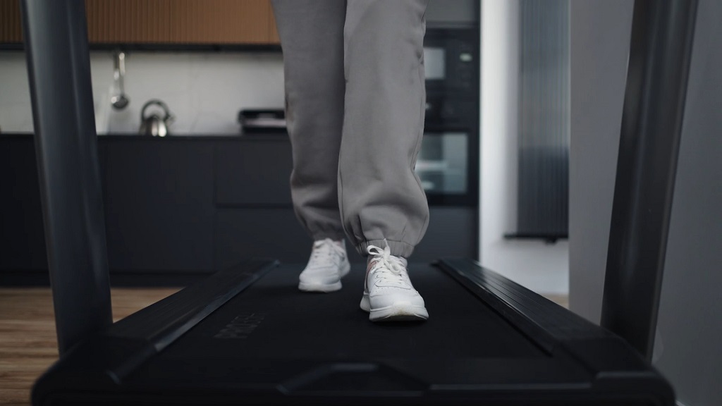 Close-up of feet walking on a treadmill with an incline in a modern home gym